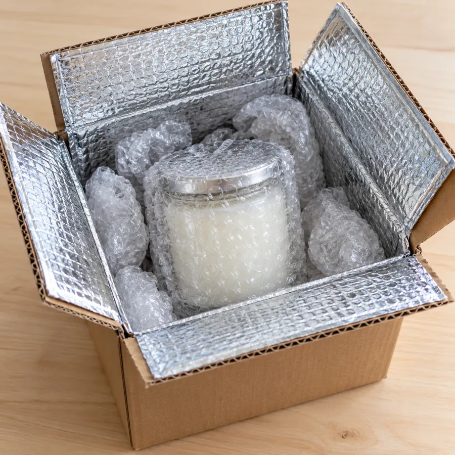 Bubble-wrapped jar candle inside a box lined with a silver insulated liner